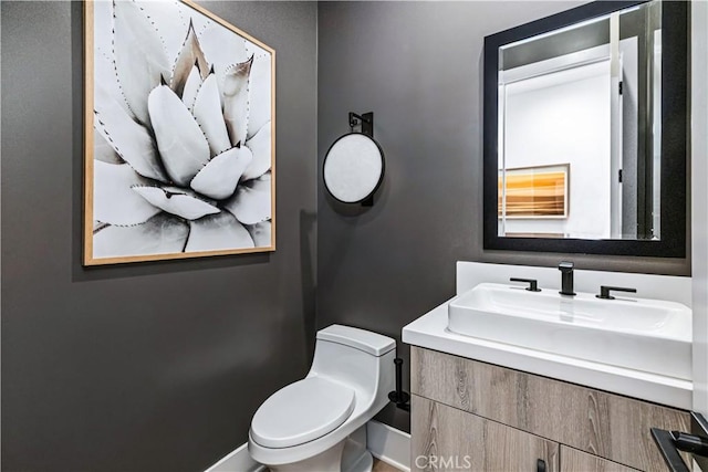 bathroom with toilet, vanity, and baseboards