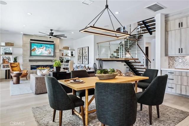 dining area with stairway, recessed lighting, light wood-type flooring, a ceiling fan, and a fireplace