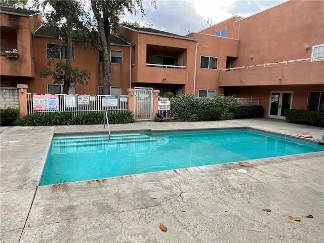 community pool with french doors and fence