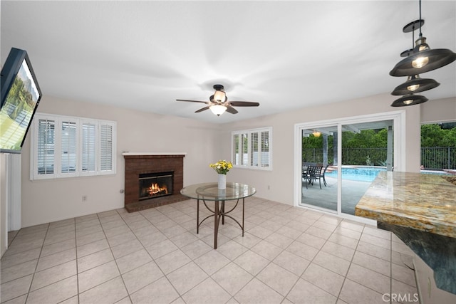 living room featuring a ceiling fan, a fireplace, and light tile patterned floors