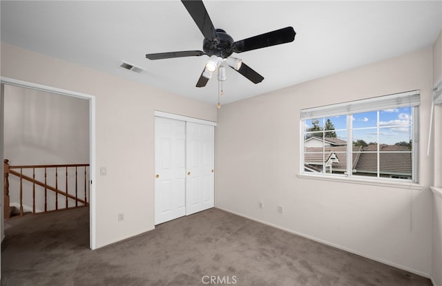 unfurnished bedroom featuring carpet floors, a closet, baseboards, and ceiling fan