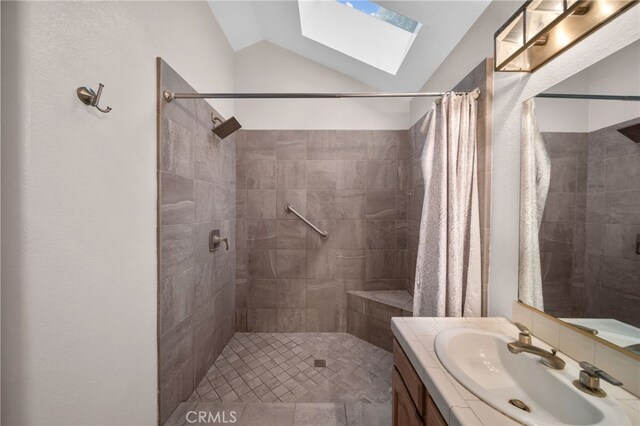 full bathroom featuring a skylight, lofted ceiling, a tile shower, and vanity