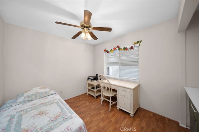 bedroom featuring light wood-type flooring, a ceiling fan, and an office area