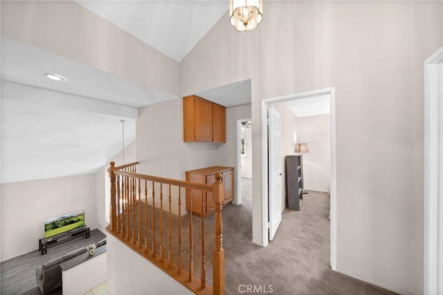 hall with an upstairs landing, light carpet, and high vaulted ceiling