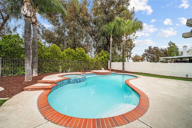 view of swimming pool featuring a fenced backyard, a pool with connected hot tub, view of wooded area, and a patio area