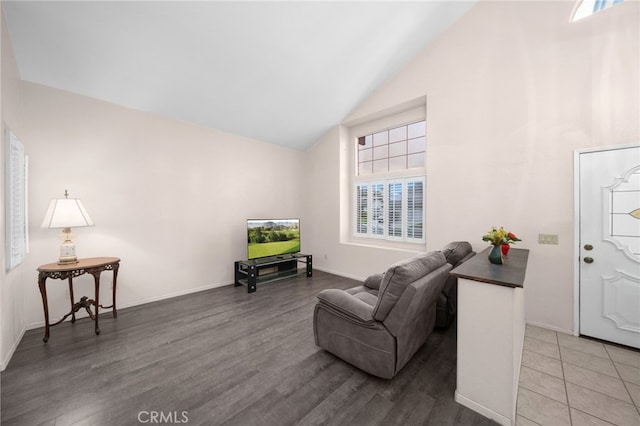 living area featuring high vaulted ceiling, plenty of natural light, wood finished floors, and baseboards