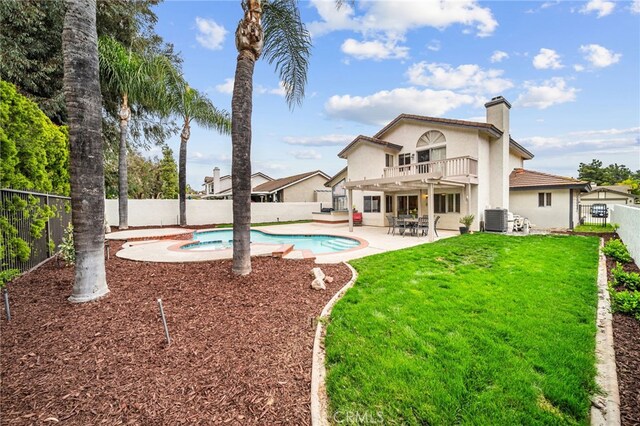 back of house featuring a balcony, central air condition unit, stucco siding, a patio, and a chimney