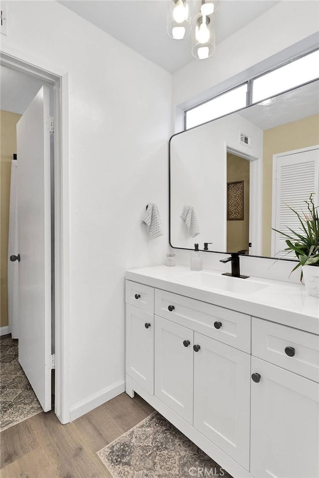 6154 Goldenrod Ln, Riverside, CA 92504 - bathroom featuring wood finished floors, baseboards, vanity, and a chandelier