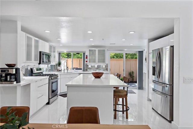 1225 Via Presa, San Clemente, CA 92672 - kitchen featuring appliances with stainless steel finishes, a breakfast bar, a sink, a kitchen island, and tasteful backsplash