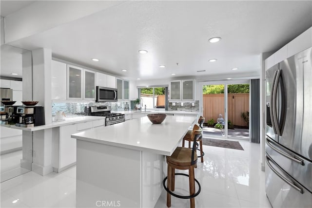 1225 Via Presa, San Clemente, CA 92672 - kitchen featuring appliances with stainless steel finishes, a kitchen bar, white cabinets, backsplash, and light tile patterned floors