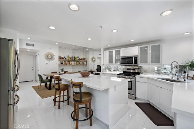 1225 Via Presa, San Clemente, CA 92672 - kitchen featuring stainless steel appliances, a sink, white cabinetry, a breakfast bar area, and a kitchen island