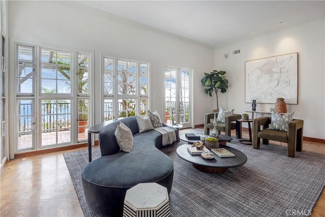 living room featuring healthy amount of natural light, baseboards, ornamental molding, and a high ceiling