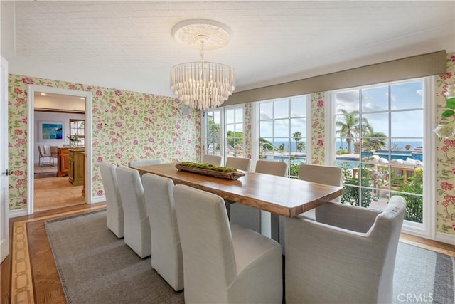 dining space with wallpapered walls, a chandelier, and baseboards