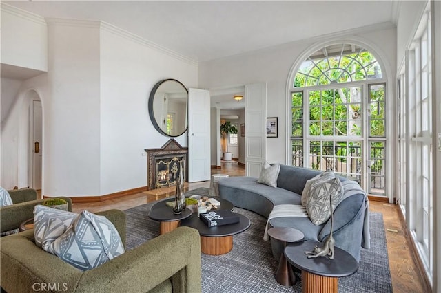 living area featuring crown molding, baseboards, and ornate columns