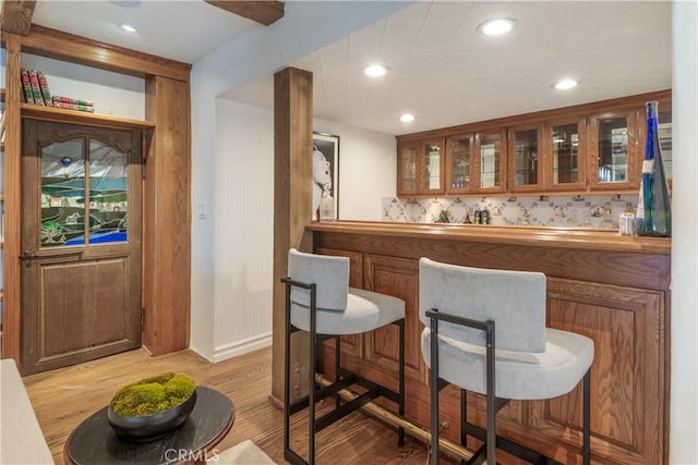 indoor bar with light wood-style floors, recessed lighting, and baseboards