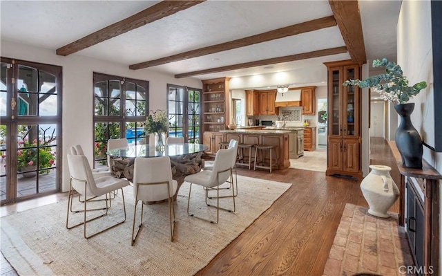 dining space featuring light wood-style flooring and beam ceiling