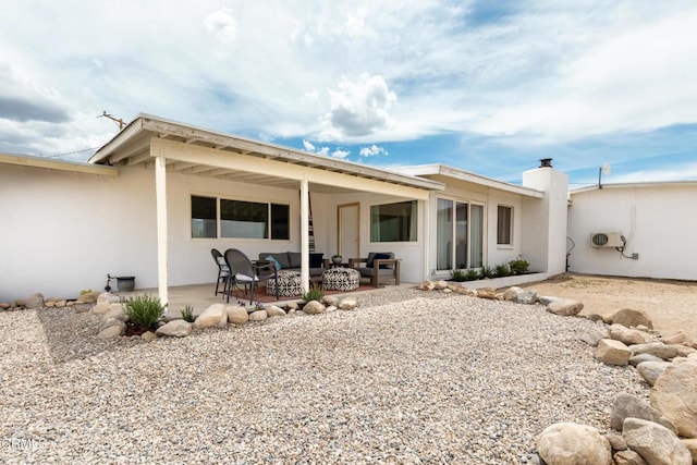 back of property with an outdoor hangout area, a patio, and stucco siding