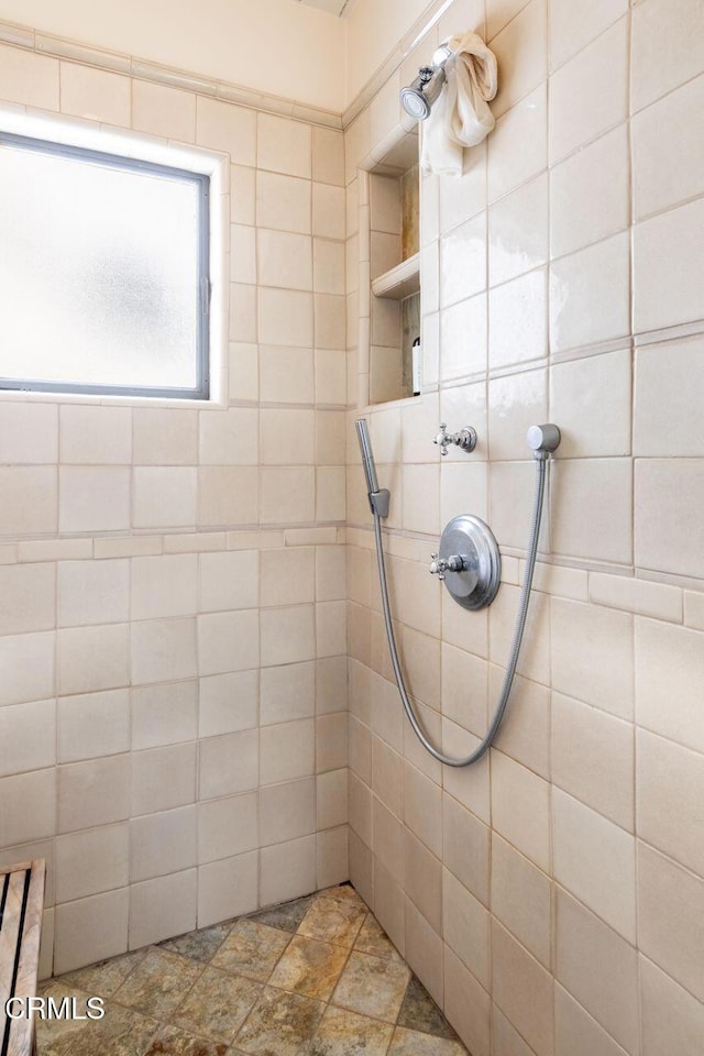 bathroom featuring a tile shower and stone finish floors