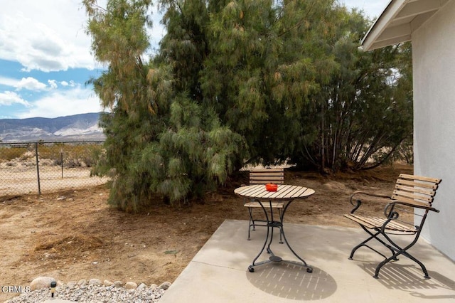 view of patio / terrace with fence and a mountain view