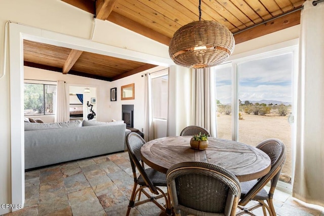 dining space with wooden ceiling, light stone finish flooring, a fireplace, and a mountain view