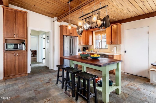 kitchen featuring wood ceiling, stainless steel appliances, tasteful backsplash, dark stone finish floors, and decorative light fixtures