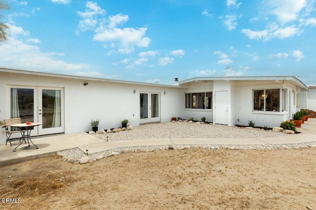 rear view of property featuring french doors, a patio area, and stucco siding