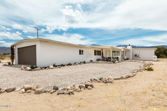 rear view of property featuring stucco siding and a garage