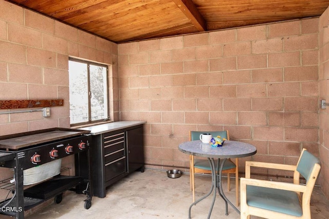dining area featuring wooden ceiling, concrete floors, and concrete block wall