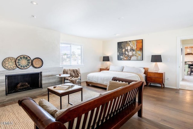 bedroom with a premium fireplace, wood finished floors, baseboards, and recessed lighting