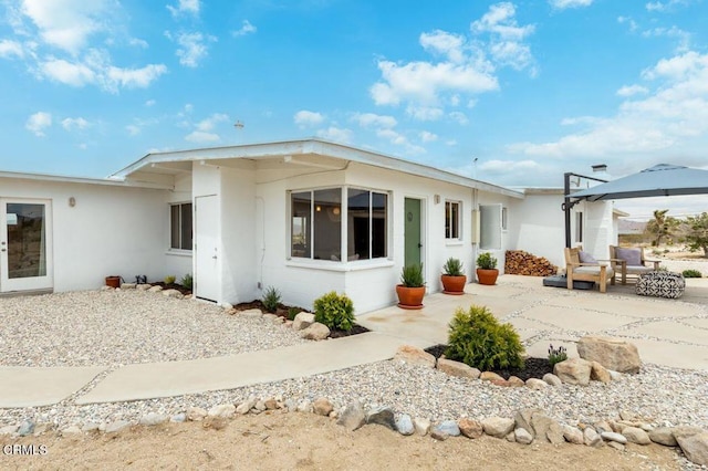 rear view of house with a gazebo, a patio area, and stucco siding