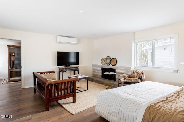 bedroom with a wall unit AC, wood finished floors, and baseboards