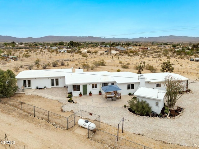 back of house featuring view of desert, a mountain view, and a fenced backyard