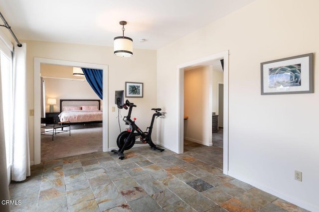 hallway featuring stone finish flooring and baseboards