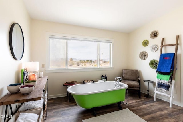 bathroom featuring wood finished floors, a freestanding tub, and baseboards