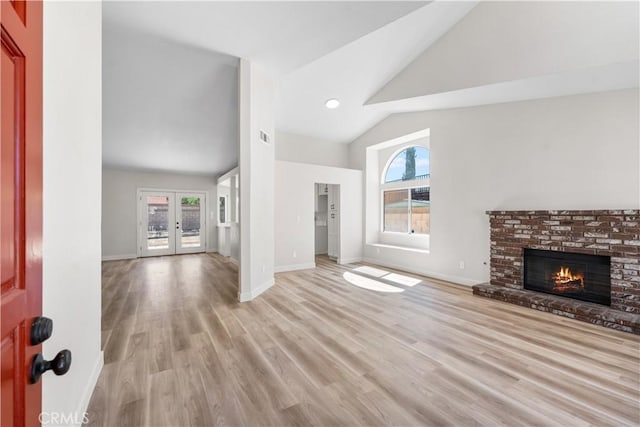 1032 Glenn Ct, Lancaster, CA 93535 - unfurnished living room featuring a brick fireplace, light wood-style flooring, baseboards, french doors, and high vaulted ceiling