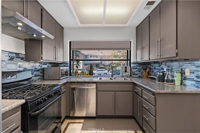kitchen featuring appliances with stainless steel finishes, a sink, under cabinet range hood, and decorative backsplash