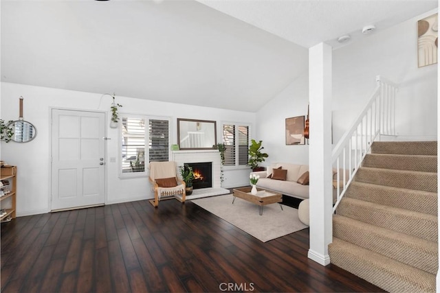 living room featuring wood finished floors, stairway, a fireplace, baseboards, and high vaulted ceiling