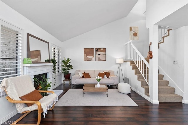 living area with stairway, lofted ceiling, wood-type flooring, a fireplace, and baseboards