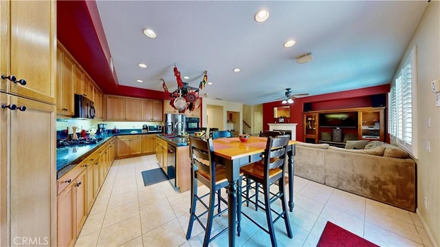 29456 Green Side Ct, Murrieta, CA 92563 - kitchen with black microwave, dark countertops, a fireplace, a ceiling fan, and light tile patterned flooring