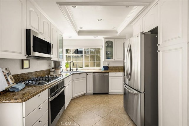 kitchen featuring stainless steel appliances, a sink, a tray ceiling, white cabinets, and crown molding