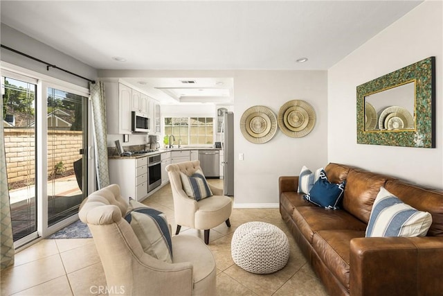 living room with light tile patterned floors, baseboards, recessed lighting, and a tray ceiling