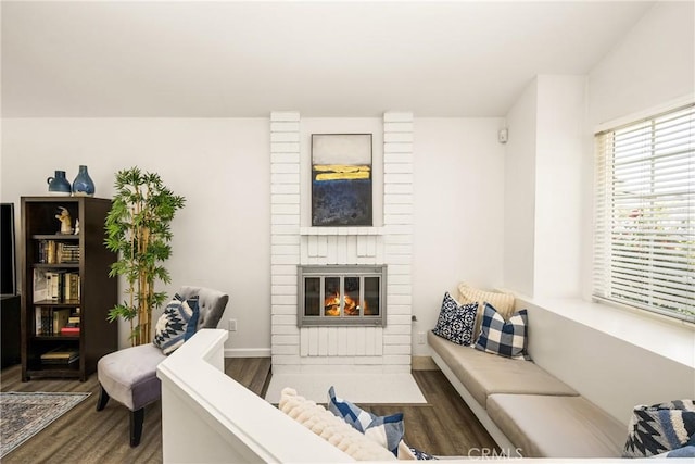 living room with wood finished floors and a brick fireplace
