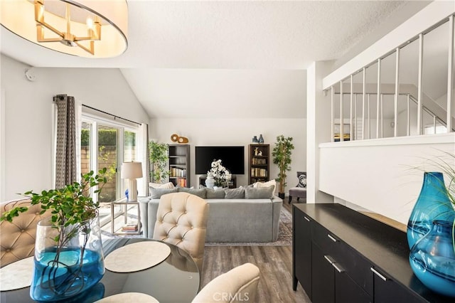 living room featuring dark wood finished floors, vaulted ceiling, and a chandelier