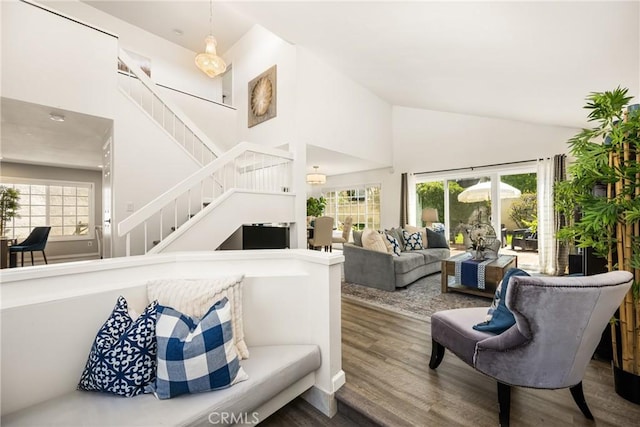 living room with high vaulted ceiling, wood finished floors, and stairway