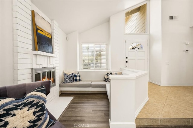 tiled living area with a fireplace, baseboards, and high vaulted ceiling