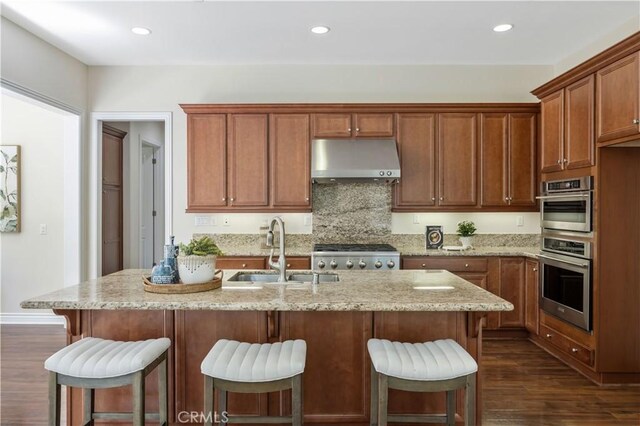 51 Carrington, Irvine, CA 92620 - kitchen with under cabinet range hood, range, dark wood-style floors, light stone countertops, and backsplash