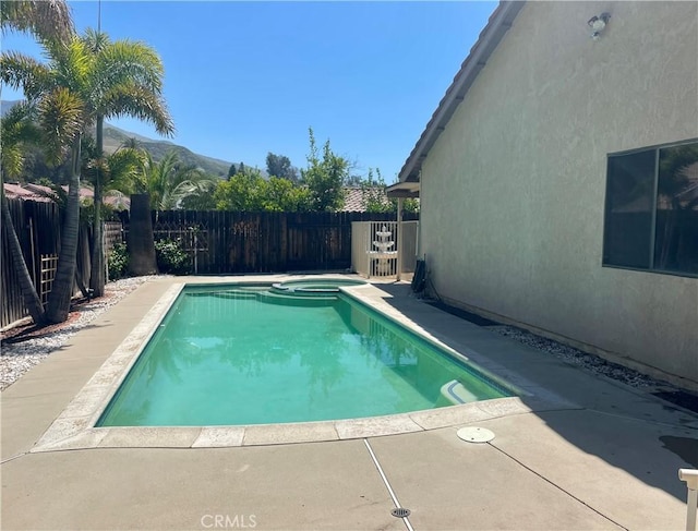 view of swimming pool featuring a fenced backyard, a pool with connected hot tub, and a patio area