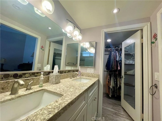 bathroom with double vanity, a spacious closet, and wood finished floors
