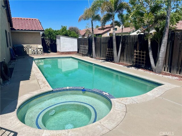 view of pool with a pool with connected hot tub, a patio, and a fenced backyard