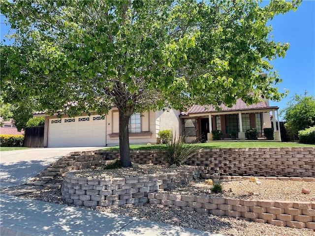 view of property hidden behind natural elements featuring concrete driveway, a garage, and stucco siding